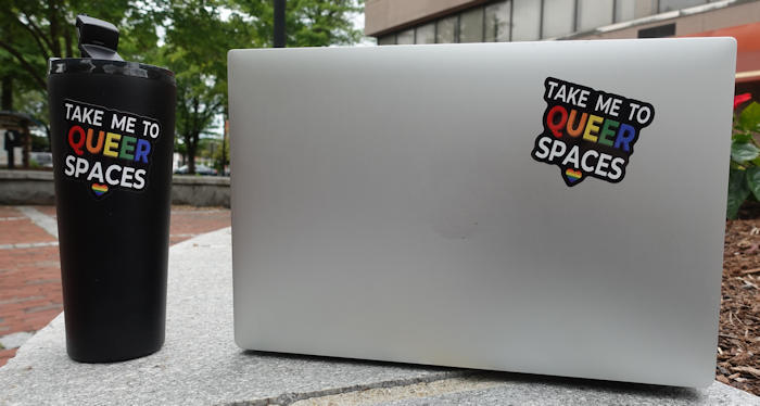 TAKE ME TO QUEER SPACES sticker on a laptop